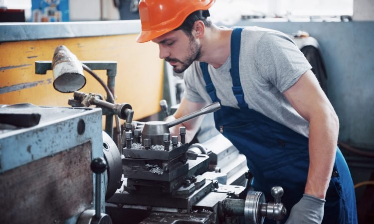 Portrait of a young worker in a hard hat at a large waste recycling factory. The engineer monitors the work of machines and other equipment.